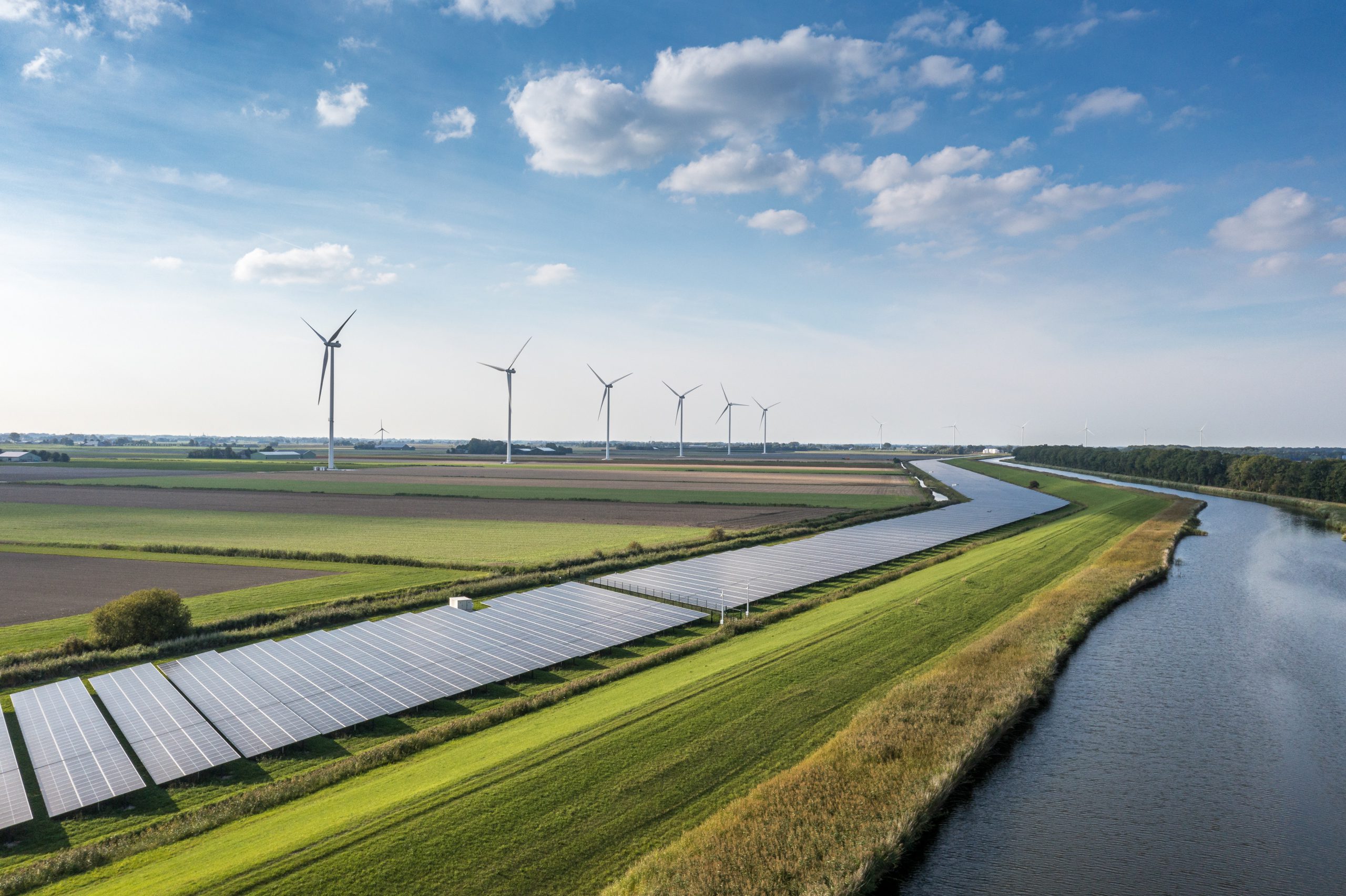 Solar panels and wind turbines beside a river
