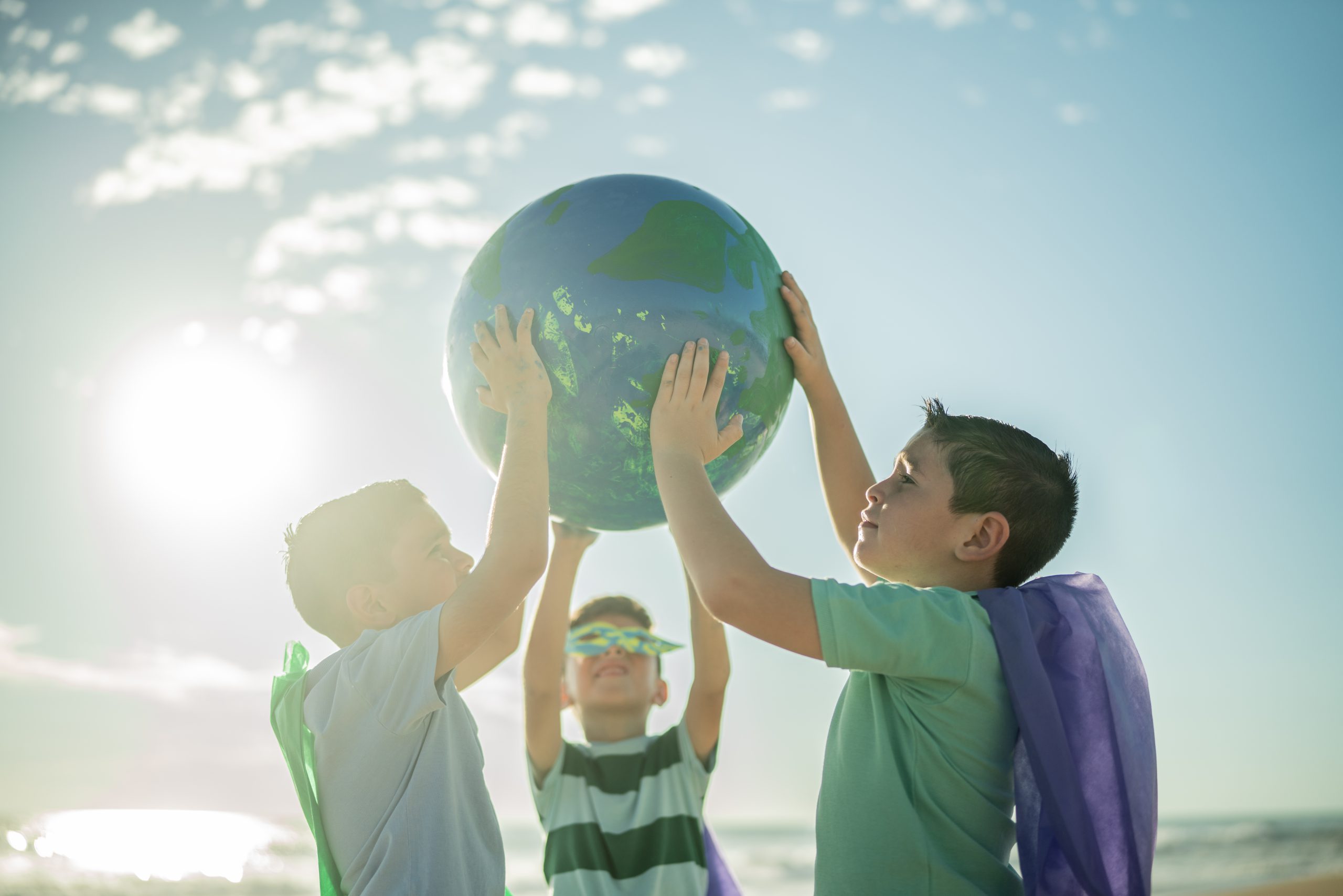 Children lifting a globe outdoors